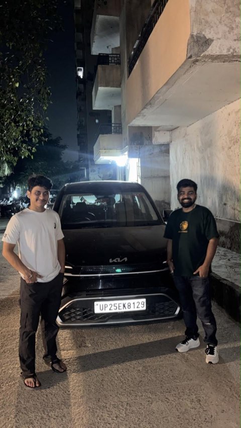 Two smiling customers with a black Kia booked for a weekend self drive car rental in Noida
